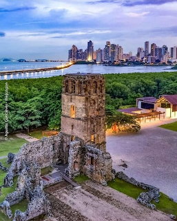 Ancient stone tower ruins with Panama City skyline and bay in background at dusk