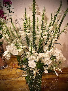 Large bouquet of white snapdragons, hydrangeas, and baby's breath with green foliage