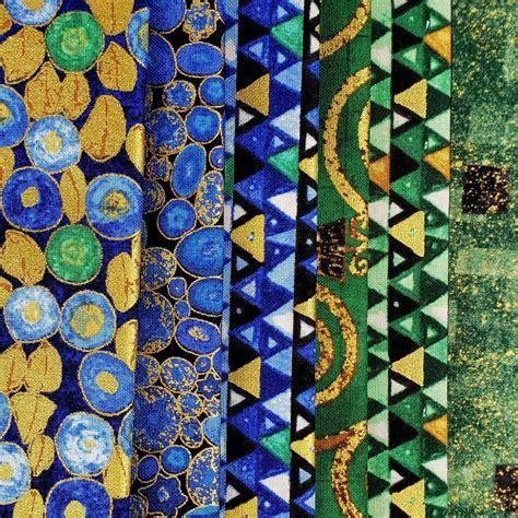 Several strips of Klimt-inspired fabric in blue, gold, and green with geometric and circular patterns