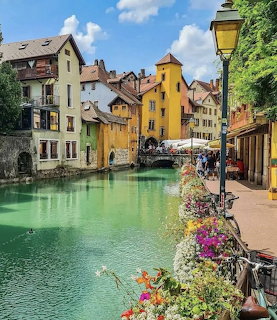 Turquoise canal lined with colorful old buildings and flowers in Annecy, France