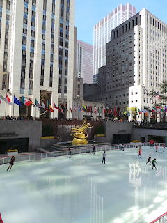 Rockefeller Center ice rink with golden Prometheus statue, flags, and skyscrapers in New York City