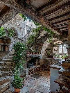 Rustic stone kitchen interior with wood beams, plants, stairs, and arched walls