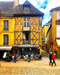 Half-timbered medieval buildings with a creperie on a cobblestone street in Sarlat, France