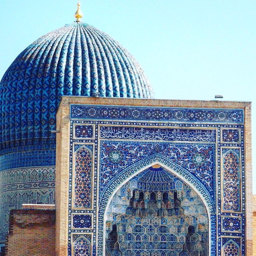 Blue tiled dome and ornate arch facade of a historic Islamic building in Samarkand