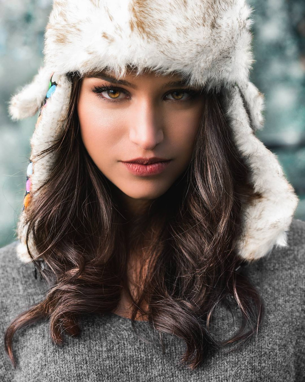 Portrait of a woman with long dark hair wearing a fluffy fur hat and gray sweater