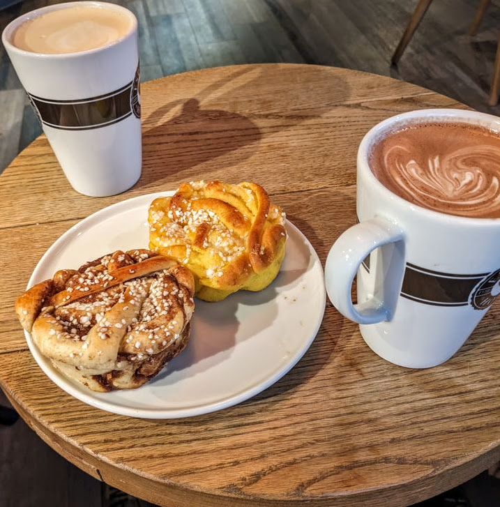 Two cups of coffee and pastries on a small round wooden cafe table