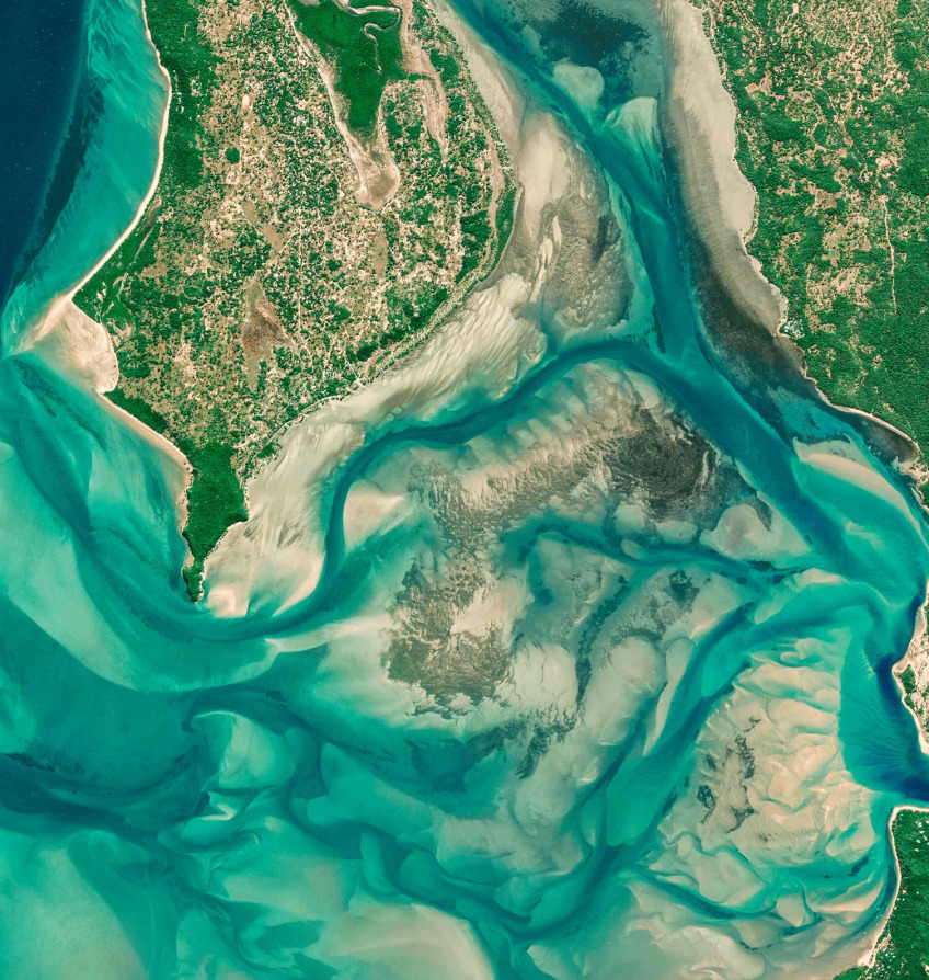 Aerial view of turquoise water, sandbars, and green coastline