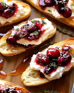 Toasted crostini topped with creamy cheese and glazed berries on wooden surface