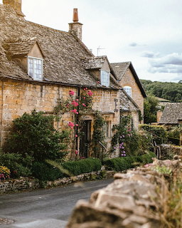 Old stone cottage with thatched roof and flowering garden
