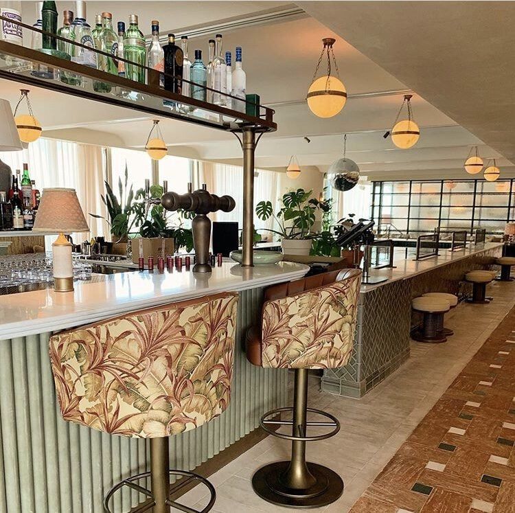 Stylish bar interior with patterned stools, hanging lights, and bottles above the counter