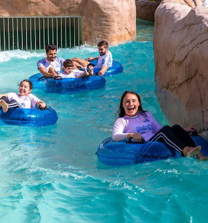 Group of people relaxing on blue tubes in a turquoise lazy river with rock walls