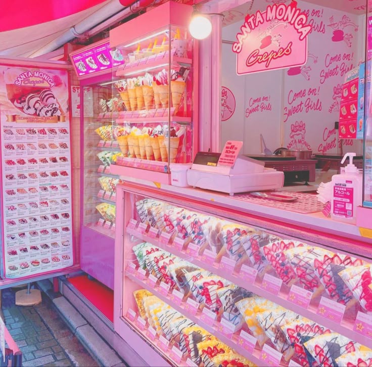 Pink-lit crepe shop interior with menu board, counter, and refrigerated display case