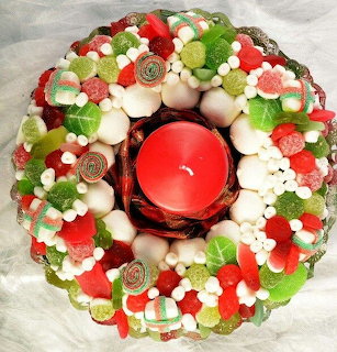Circular wreath of red, green, white candy with flowers around red candle