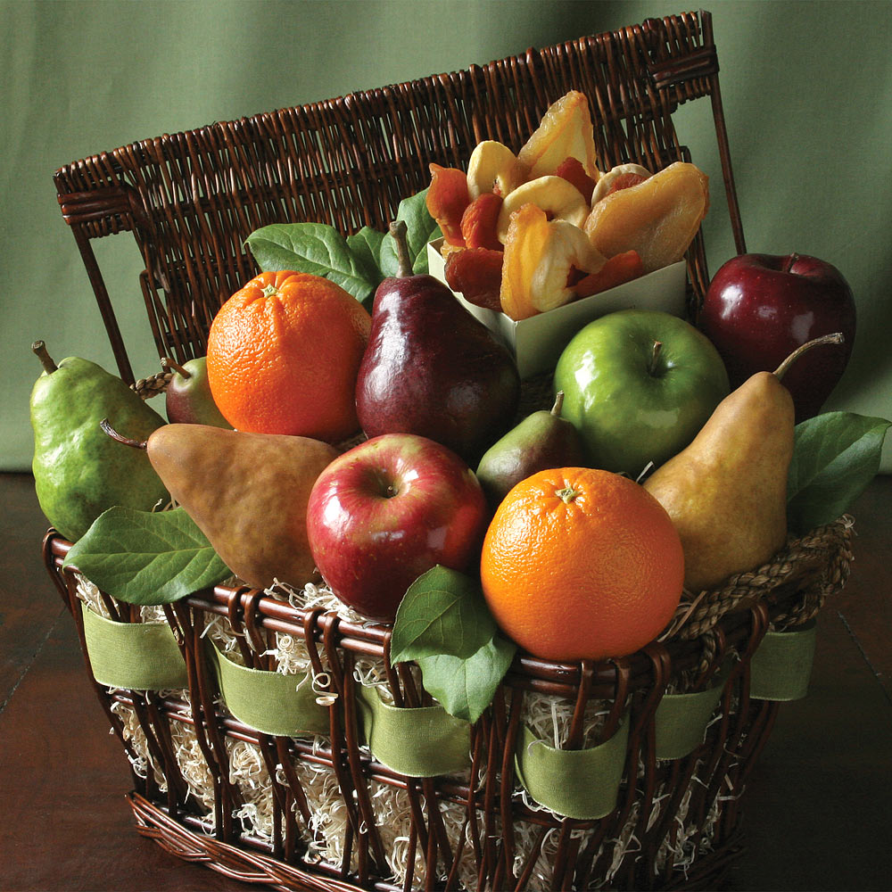 Wicker basket overflowing with assorted fresh fruit including apples, oranges, pears and bananas tied with green ribbon