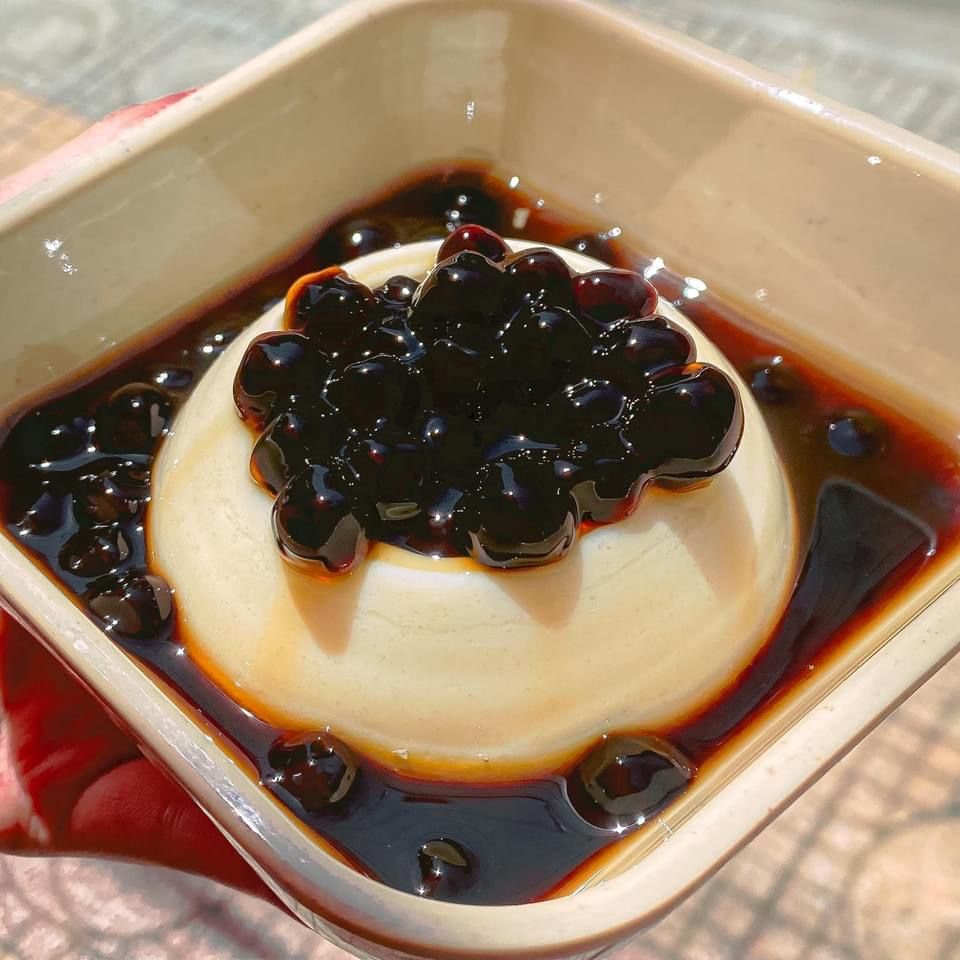 Creamy pudding topped with black tapioca pearls and syrup in a square bowl