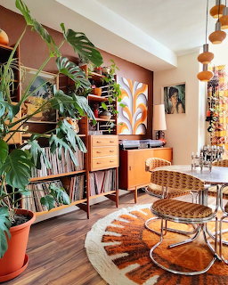 Bright living room with houseplants, wooden furniture, pendant lights and earth-tone rug
