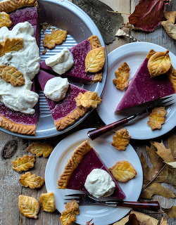 Purple sweet potato pie with leaf-shaped crust decorations and whipped cream on rustic wooden table
