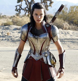 Woman wearing medieval warrior costume with armor standing in desert setting