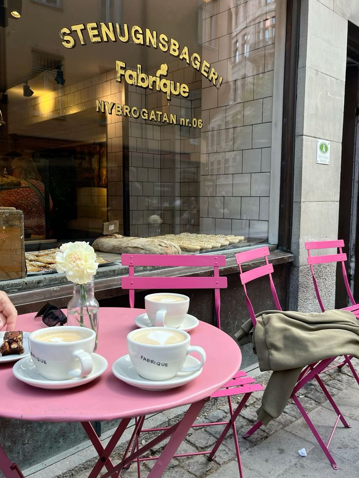 Pink bistro table and chairs with coffee cups outside Fabrique bakery in Stockholm