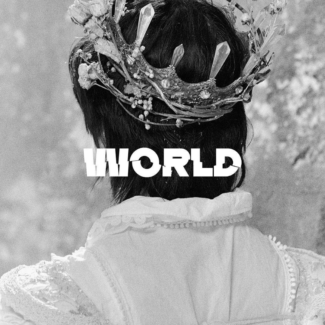 Black-and-white back view portrait of a person with a branch crown and white blouse, with WORLD text overlay