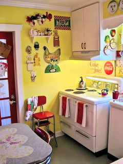 Vintage kitchen with yellow walls, white cabinets, retro appliances, and rooster decorations