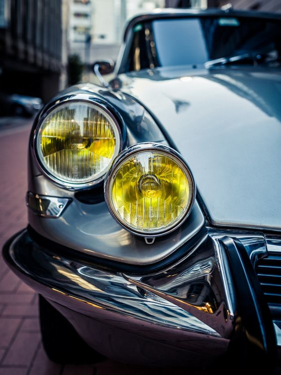 Close-up of classic white car with chrome bumper and yellow circular headlights