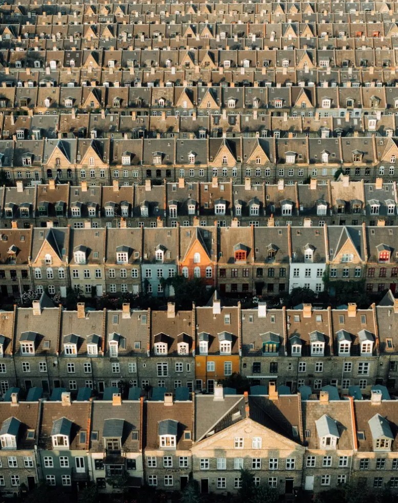 Aerial view of dense rows of uniform townhouses with terracotta rooftops in a European city