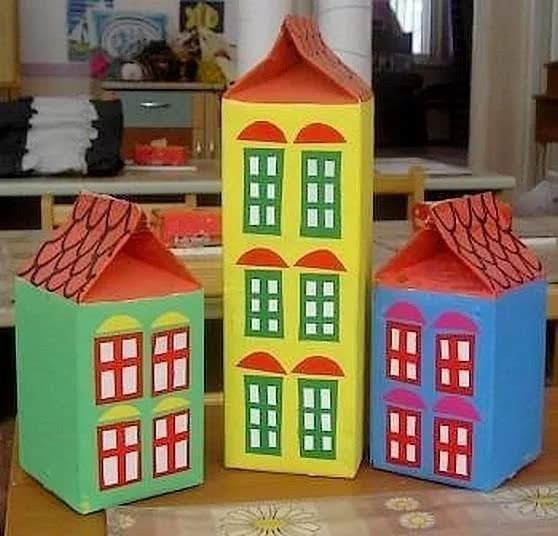 Three colorful paper house crafts with red roofs displayed indoors