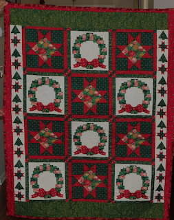 Christmas quilt with wreaths and stars in red, green, white patterns on dark green background