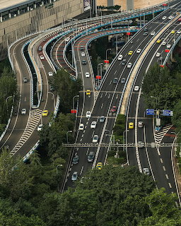Aerial view of busy multilane highways with cars on curved city overpasses