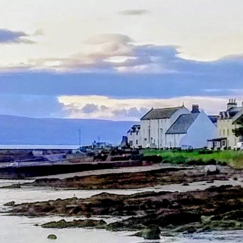 White coastal houses beside a rocky shore at dusk under a cloudy sky