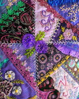 Ornate crazy quilt with embroidered purple, green and pink fabric patches, decorative stitching and ribbon work