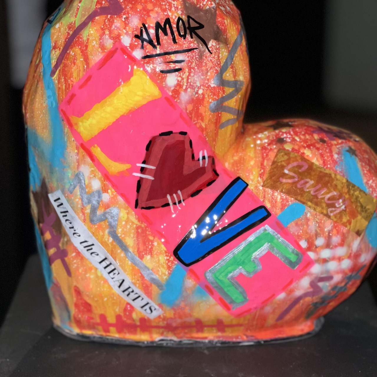 Colorful heart-shaped sculpture with graffiti-style painting featuring LOVE text and bright splatter patterns
