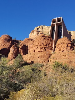 Modern chapel among red rock formations and desert shrubs in Sedona under a blue sky.