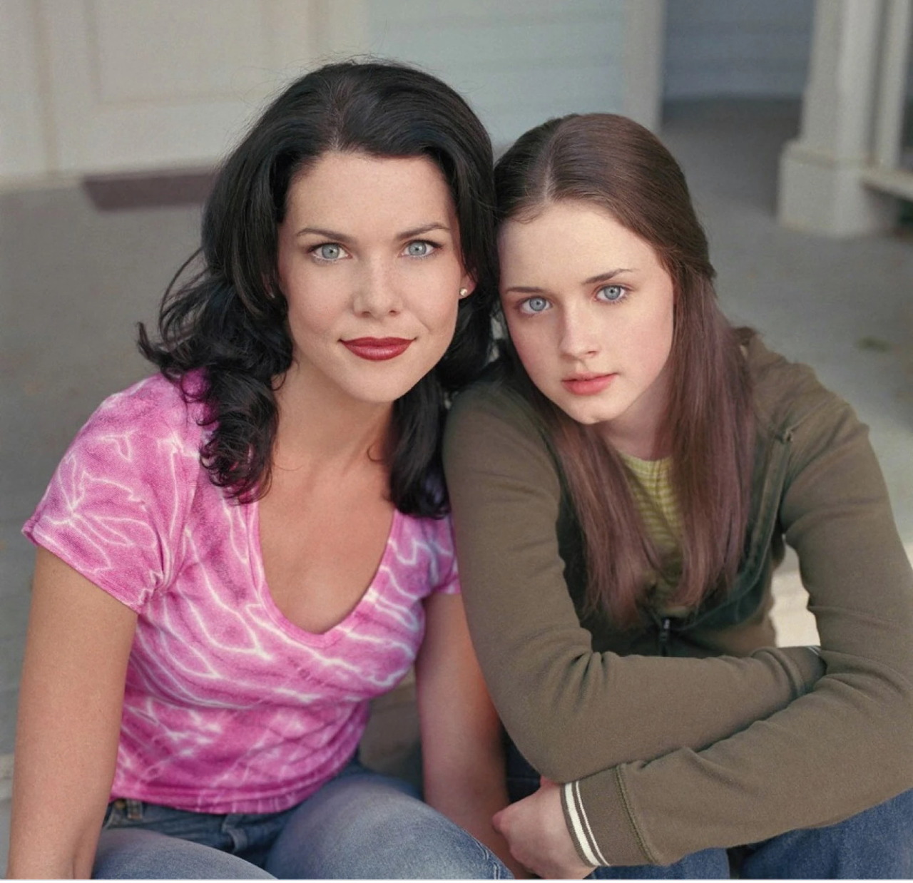 Two women sitting closely together indoors, facing the camera