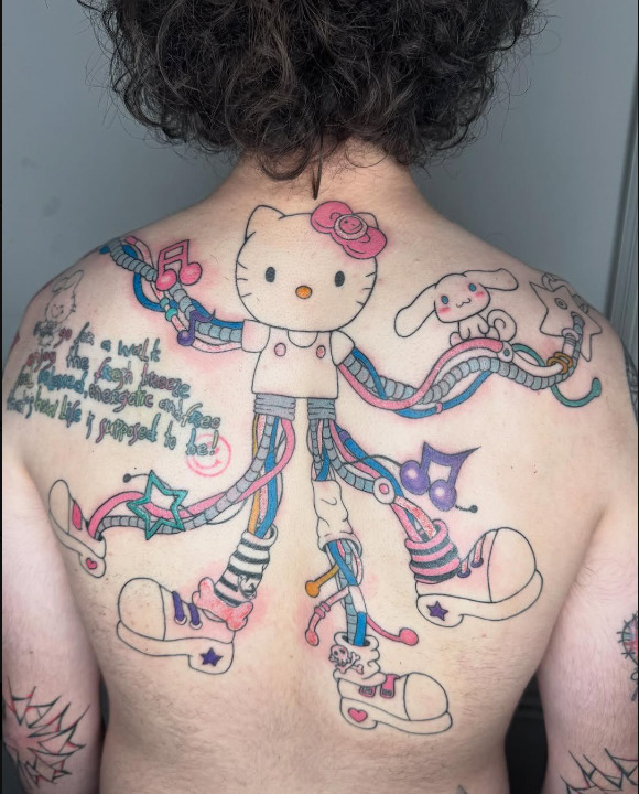Colorful Hello Kitty and Sanrio characters tatooed across a person's upper back with ribbons and script