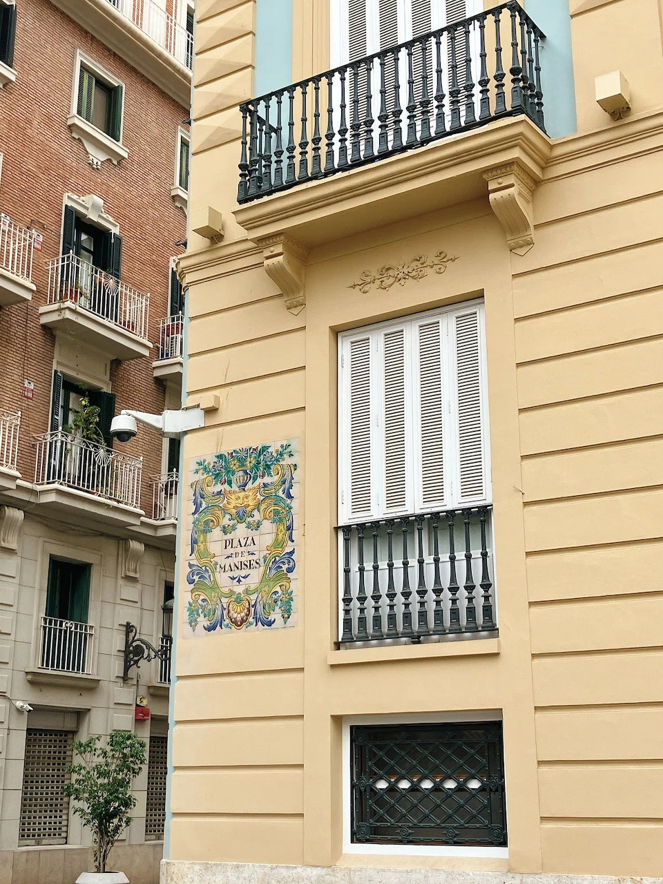 Beige apartment building facade with balconies and a decorative ceramic sign in Valencia, Spain