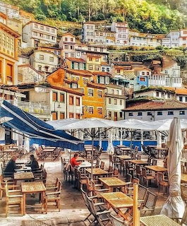Outdoor café seating beneath colorful hillside houses in Cudillero, Asturias, Spain