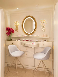 Luxurious nail salon station with oval mirror, cream drawers, white modern chairs, and pink flowers