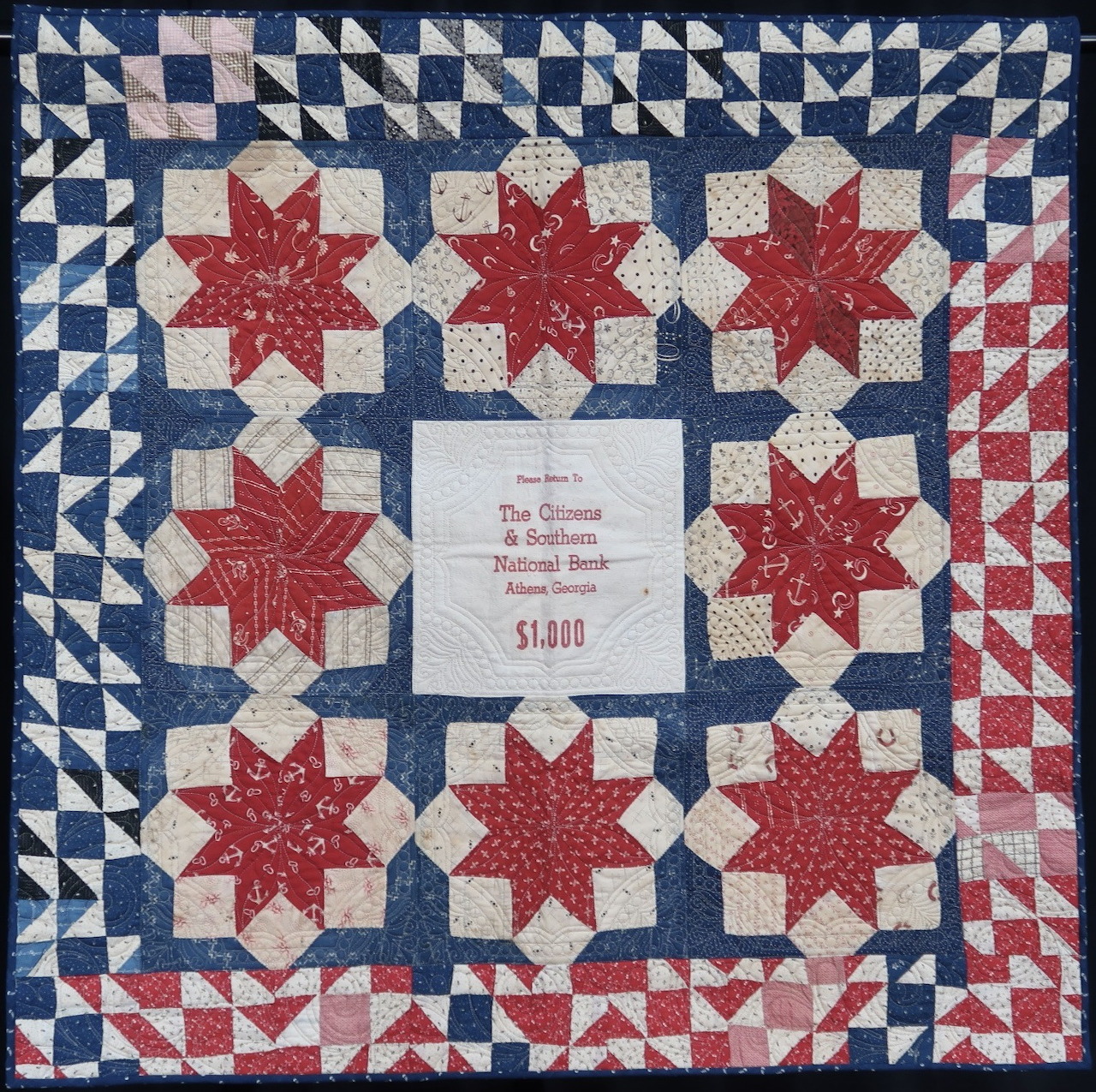 Patriotic quilt with red stars, blue borders, and triangular edge pattern in red, white, and blue