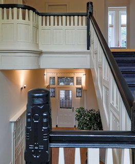 Interior view of elegant black and white staircase with decorative railing and white paneled walls