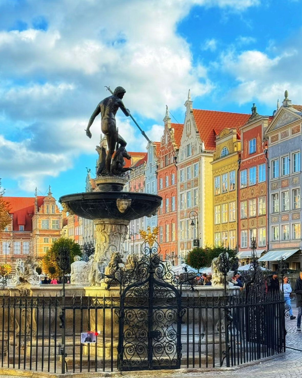 Bronze Neptune fountain statue in front of colorful historic buildings in Gdansk, Poland