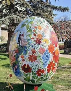 Giant white egg sculpture painted with colorful flowers standing in a park