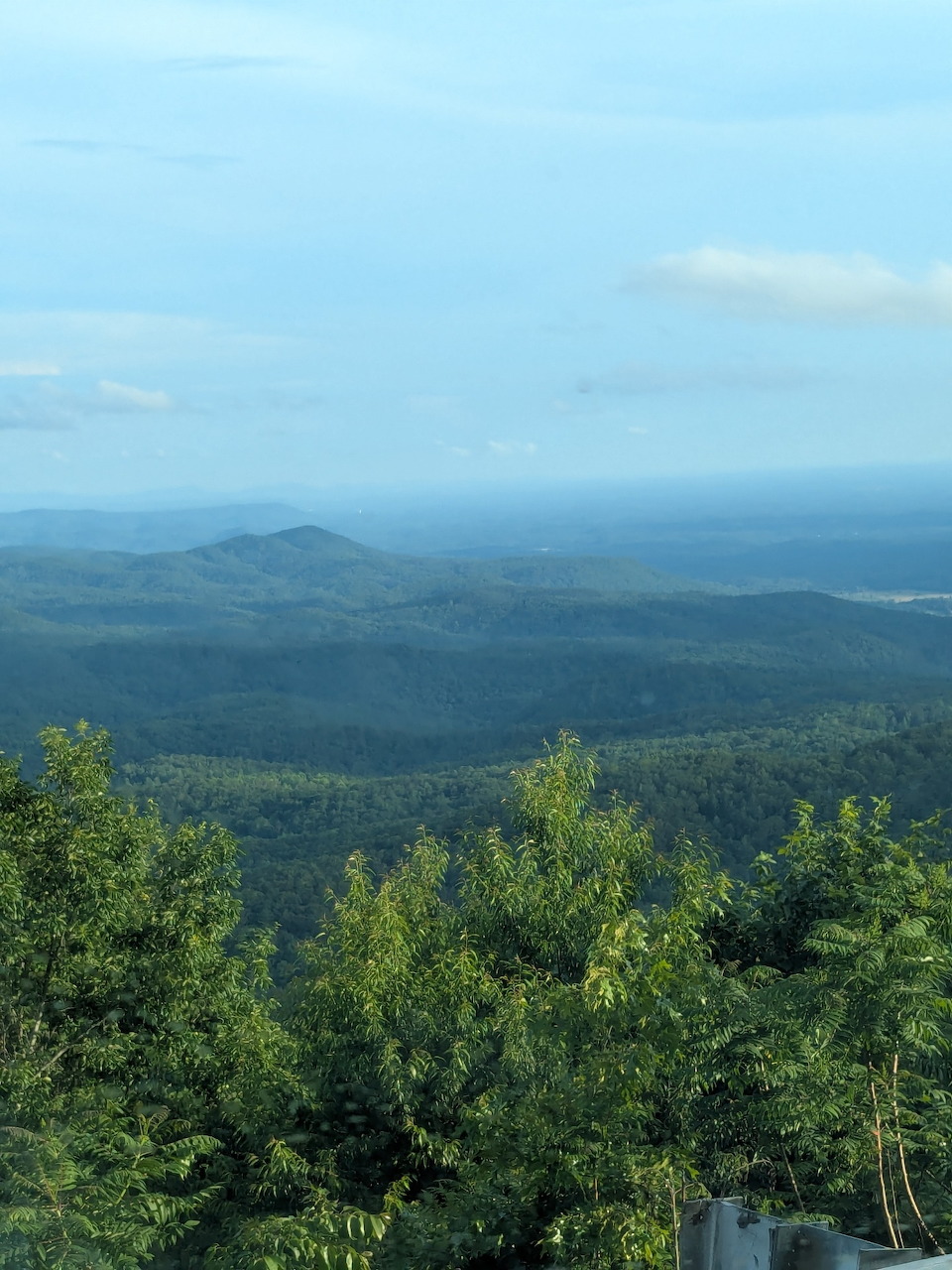 Elevated view of green forested Georgia mountain ridges fading into a hazy blue sky