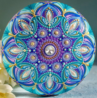 Circular mandala with intricate dot painting in blue, purple, and turquoise with symmetrical patterns
