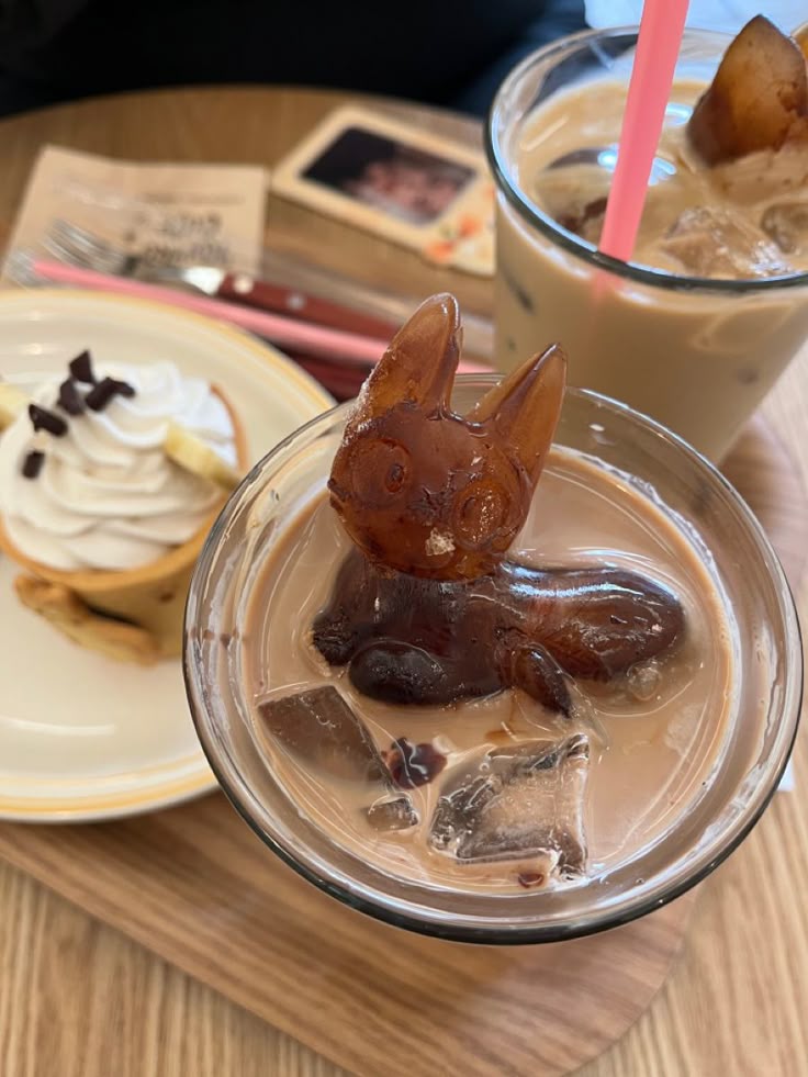Eevee-shaped jelly in an iced coffee glass at a Pokemon cafe, with a cream dessert in the background