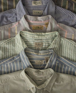 Five folded striped button-down shirts stacked on top of each other in blue, green, and gray tones
