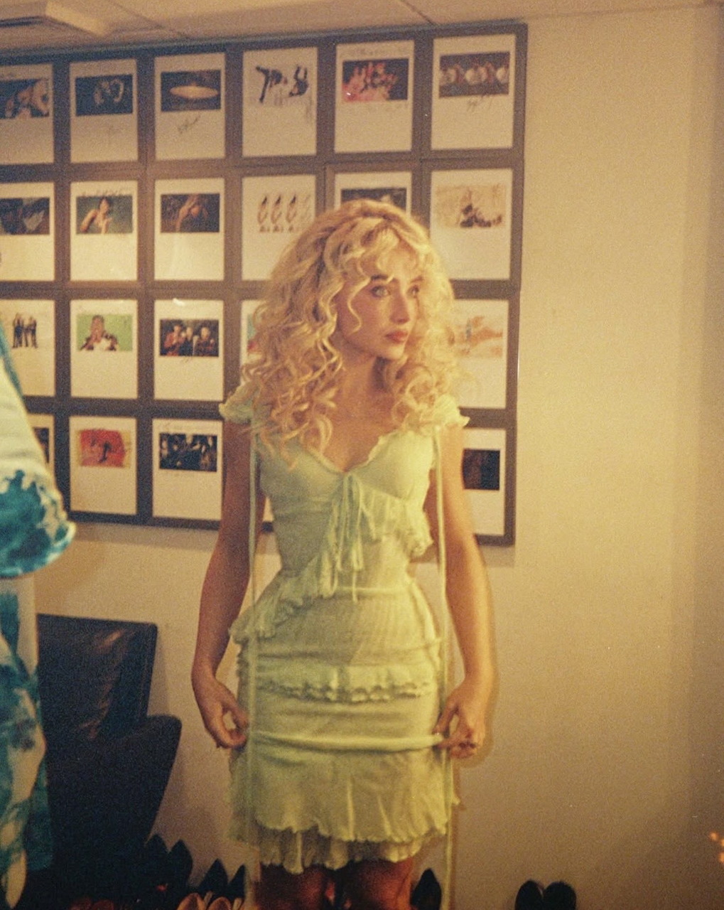 Woman in mint green lace dress performing on stage with photo wall backdrop