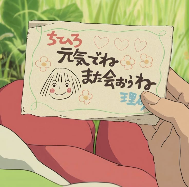 Anime-style hand holding a handwritten note with doodles above red clothing and green grass