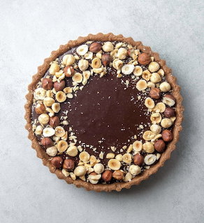 Top view of a chocolate hazelnut tart on a light gray surface